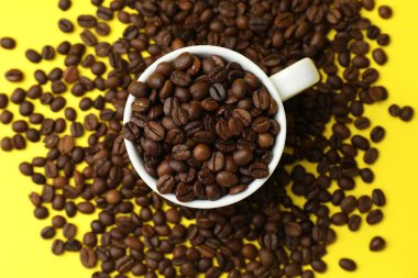 Aromatik kahve çekirdekleri ve fincanlar sarı arka planda, düz yatıyordu.