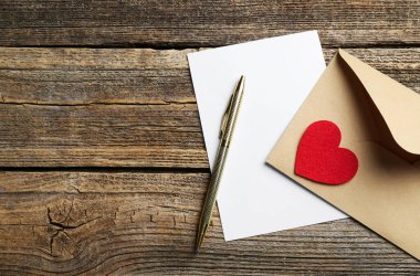 Zarfta aşk mektubu, kırmızı kalp ve tahta masa üzerindeki kalem, düz. Metin için boşluk