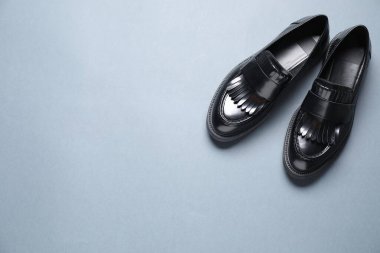 Gri arka planda bir çift şık siyah mokasen ayakkabı, düz. Metin için boşluk