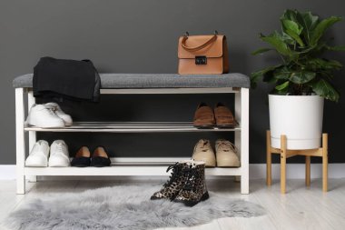 Gri duvarın yanında farklı ayakkabı, çanta ve çiçek depoları var.