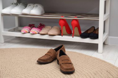 Açık gri duvarın yanında farklı ayakkabıları olan ayakkabı tezgahı, kapalı.