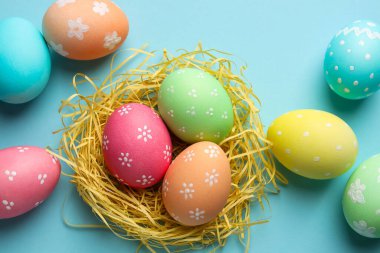 Birçok boyanmış Paskalya yumurtası ve saman açık mavi arka planda, düz yatıyordu.