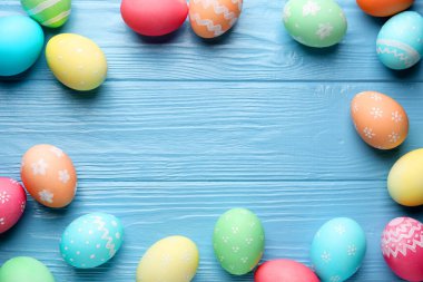 Açık mavi ahşap masa üzerinde güzel dekore edilmiş Paskalya yumurtaları. Metin için boşluk