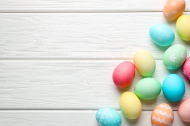 Süslü Paskalya yumurtaları beyaz ahşap masada, düz yerde. Metin için boşluk
