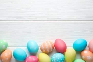 Süslü Paskalya yumurtaları beyaz ahşap masada, düz yerde. Metin için boşluk