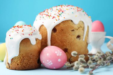 Lezzetli Paskalya pastaları, süslenmiş yumurtalar ve açık mavi arka planda söğüt dalları, yakın plan.