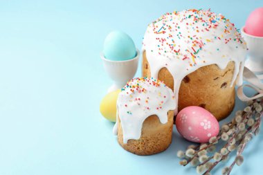 Lezzetli Paskalya pastaları, süslenmiş yumurtalar ve açık mavi arka planda söğüt dalları, yakın plan. Metin için boşluk