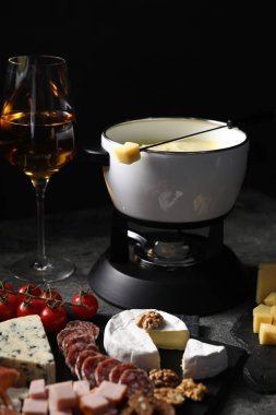Erimiş peynir, şarap ve atıştırmalıklarla fondü tenceresi (caquelon), yakın plan.