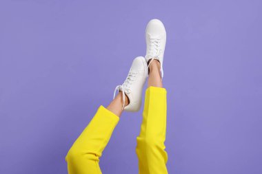 Violet 'in arka planında şık beyaz ayakkabılar giyen bir kadın, yakın plan. Metin için boşluk