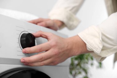 Çamaşır makinesi programını seçen kadın, yakın plan.