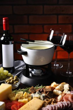 Erimiş peynir, şarap ve abur cuburla fondü tenceresi (caquelon), yakın plan.