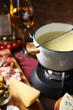 Erimiş peynir, şarap ve abur cuburla fondü tenceresi (caquelon), yakın plan.