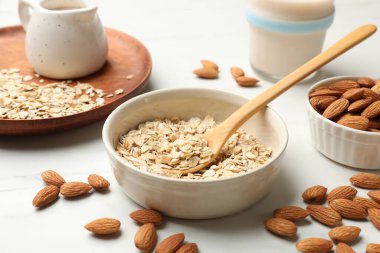 Yulaf gevreği, badem sütü ve fındıklar beyaz mermer masada, yakın plan.