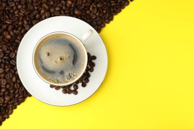 Kahveyi fincanda tazelemek ve sarı arka planda fasulye, düz uzanmak. Metin için boşluk