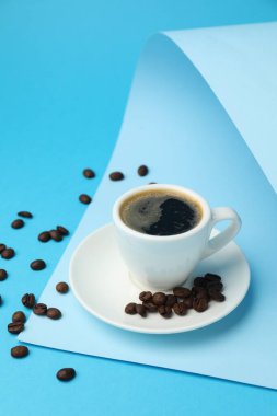 Kahveyi fincanda, fasulyeyi ve açık mavi arka planda kağıdı tazeliyorum.