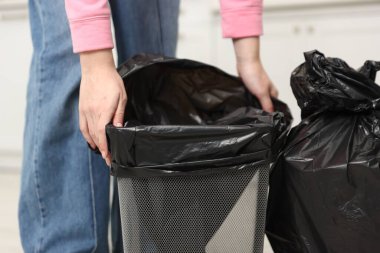 Mutfaktaki çöp kutusuna çöp torbası koyan kadın, yakın plan.