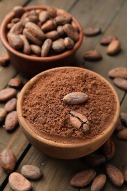 Doğal kakao çekirdeği ve toz tahta masanın üzerinde, yakın plan.