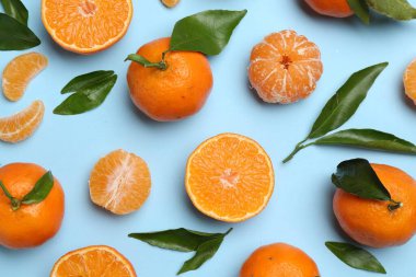 Taze, sulu mandalinalar ve açık mavi arka planda yeşil yapraklar.