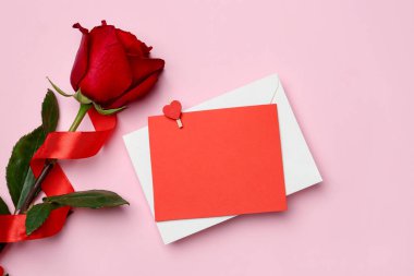 Aşk mektubu ve pembe arka planda gül, üst manzara. Metin için boşluk