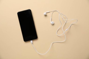 Bej arka planda kulaklıklı akıllı telefon, üst görünüm