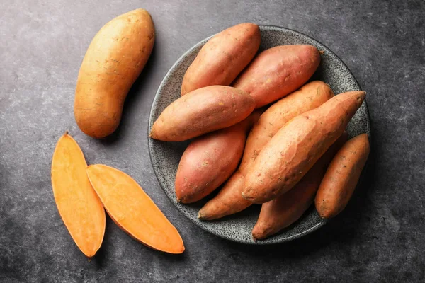 Siyah masada çiğ patates, düz uzanmış.