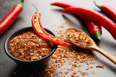 Kırmızı biber ve tanecikler gri masada, yakın plan.