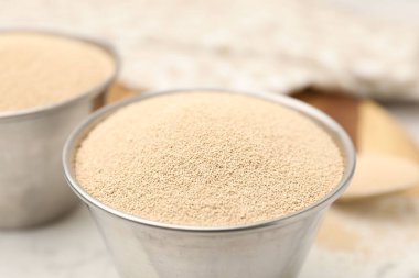 Beyaz masadaki metal kaselerde kuru maya, yakın plan.