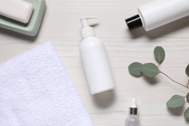 Yumuşak havlu, kozmetik ürünler ve ahşap masada yeşil yapraklar.
