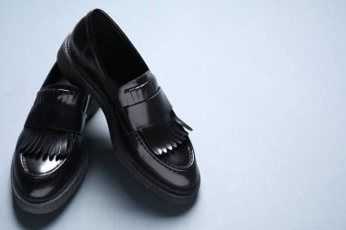 Gri arka planda bir çift şık siyah mokasen ayakkabı, yakın plan. Metin için boşluk