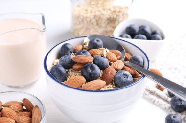 Yulaf gevreği, badem sütü, yaban mersini ve fındık beyaz masada, yakın plan.