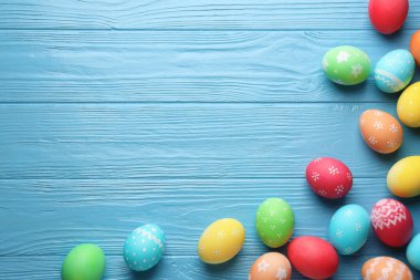 Açık mavi ahşap masa üzerinde güzel dekore edilmiş Paskalya yumurtaları. Metin için boşluk