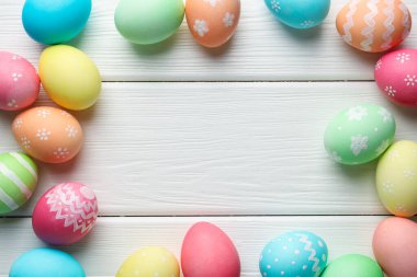 Süslü Paskalya yumurtaları beyaz ahşap masada, düz yerde. Metin için boşluk