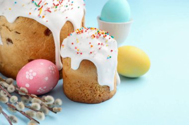 Lezzetli Paskalya pastaları, süslenmiş yumurtalar ve açık mavi arka planda söğüt dalları, yakın plan. Metin için boşluk