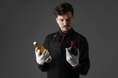 Gri arka planda şarap şişeleri olan profesyonel şarap garsonu.