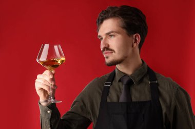 Kırmızı arka planda beyaz şarap kadehi olan profesyonel şarap garsonu.