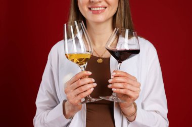 Kırmızı arka planda şarap kadehleri olan profesyonel şarap garsonu, yakın plan.