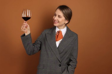 Kahverengi arka planda kırmızı şarap kadehi olan profesyonel şarap garsonu.