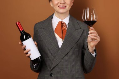 Kahverengi arka planda cam ve şarap şişesi olan profesyonel şarap garsonu.