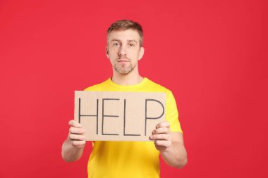 Mutsuz adam kırmızı arka planda kelime yazılı karton tabela tutuyor.