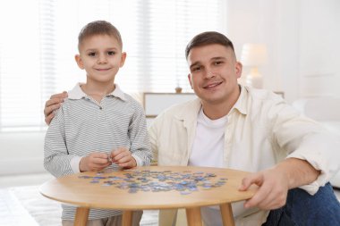 Baba ve oğlu evde yapboz çözüyorlar.