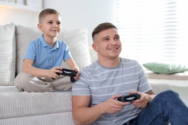 Baba ve oğlu evde video oyunu oynuyorlar.