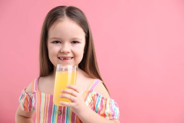 Pembe arka planda bir bardak portakal suyu olan küçük kız, mesaj için yer var.