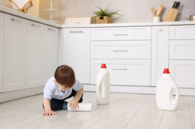 Evde çocuk güvenliği. Mutfakta temizlik malzemesi olan küçük bir çocuk.