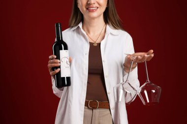 Kırmızı arka planda şarap ve gözlüklü profesyonel şarap garsonu, yakın plan.