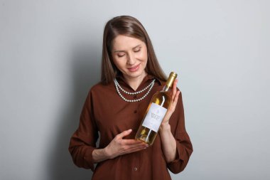 Açık gri arka planda beyaz şarap şişesi olan profesyonel şarap garsonu.