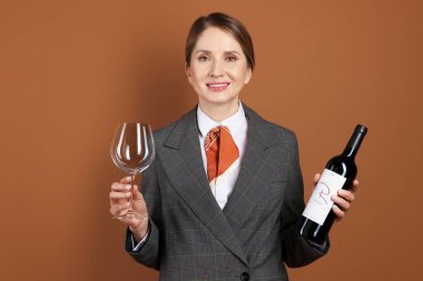 Kahverengi arka planda cam ve şarap şişesi olan profesyonel şarap garsonu.