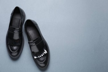 Gri arka planda bir çift şık siyah mokasen ayakkabı, düz. Metin için boşluk