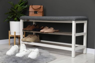 Gri duvarın yanında farklı ayakkabı, çanta ve çiçek depoları var.