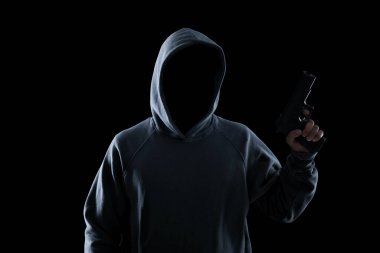 Kapüşonlu isimsiz bir suçlu siyah arka planda silah tutuyor.