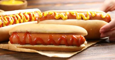 Ahşap masada hardallı lezzetli sosisli sandviç yiyen bir kadın.